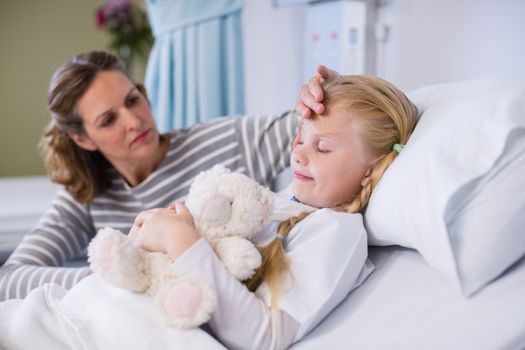 Mother comforting her daughter in hospital bed