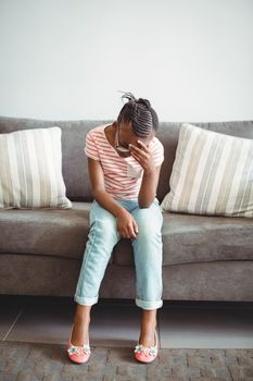 Upset girl sitting on chair in corridor at hospital