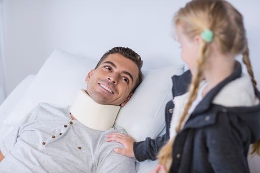 Smiling daughter comforting her sick father in hospital room