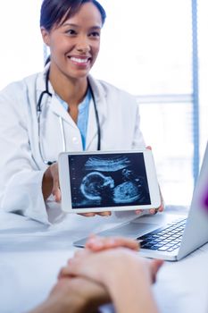 Doctor showing babies ultrasound scan on digital tablet in hospital