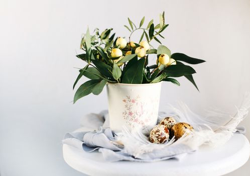 Easter eggs with green branches and yellow berries on white and gray background. Happy Easter holiday, front view.