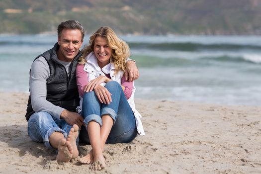 Romantic mature couple sitting together on the beach