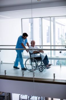 Male doctor interacting with male senior patient in the passageway at hospital