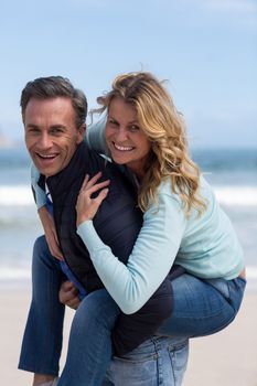 Portrait of mature man giving piggyback ride to woman on beach