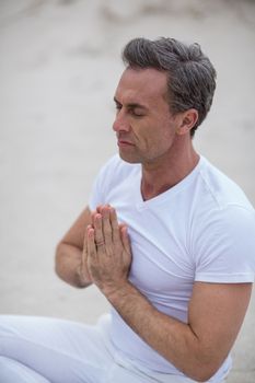 Mature man doing meditation on the beach