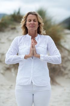 Mature woman doing meditation on the beach