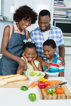 Parents and kids preparing salad in kitchen at home