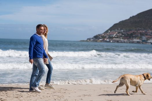 Romantic mature couple walking on the beach with their dog