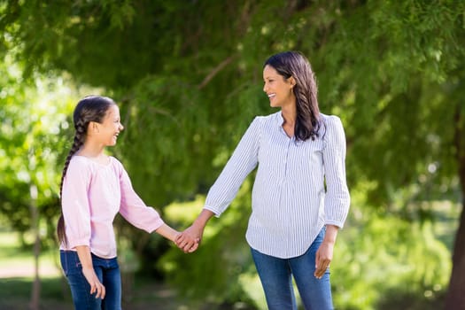 Happy mother holding hands of her daughter in park