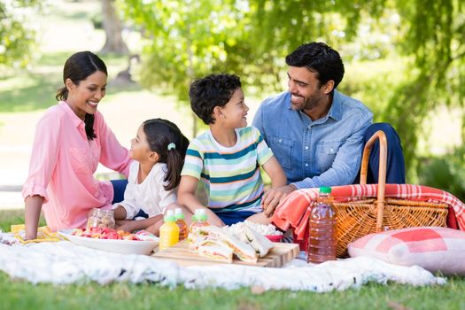 Happy family having breakfast in park on a sunny day