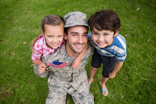 Happy soldier reunited with his son and daughter in park on a sunny day