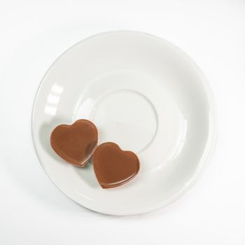 The close up of Love heart shape chocolate on coffee cup plate on white background.