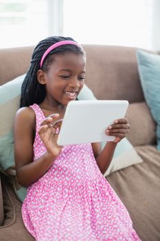 Girl sitting on sofa and using digital tablet in living room at home