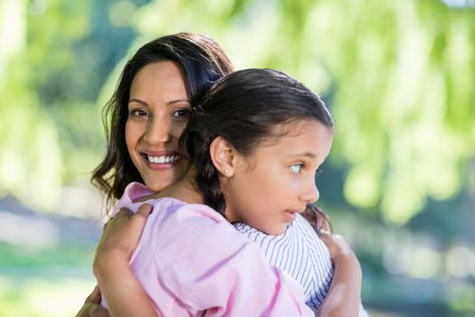 Happy mother embracing her daughter in park