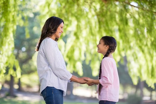 Happy mother holding hands of her daughter in park