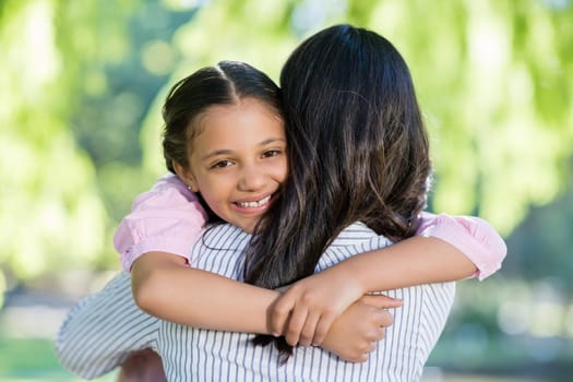 Smiling girl embracing her mother in park