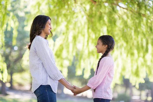 Happy mother holding hands of her daughter in park