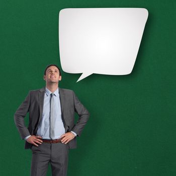 Smiling businessman with hands on hips against speech bubble