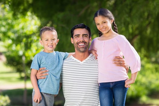 Father having fun with his son and daughter in park on a sunny day