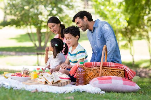 Happy family having breakfast in park on a sunny day