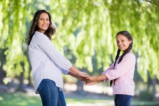Happy mother holding hands of her daughter in park