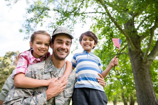 Happy soldier reunited with his son and daughter in park on a sunny day