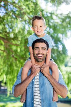 Father carrying son on his shoulders park in park on a sunny day