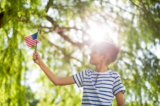 Boy holding small american flag in park on a sunny day