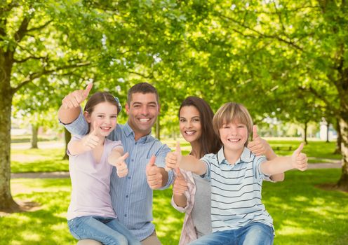 Portrait of family showing thumbs up in park
