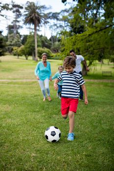 Happy family playing football in park on a sunny day