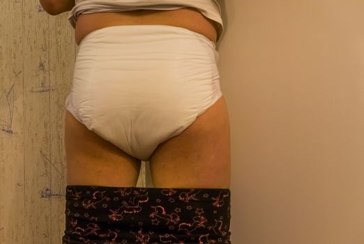 young adult person wearing a wet adult diaper, rear view, Incontinence products and solutions, medical bladder control issues
