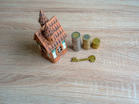 Model of a house, Stack of European Euro coins and golden key On Wooden Table. Real estate agency, mortgage loan, lottery, buying property.Home loan and investment concept. Copy space