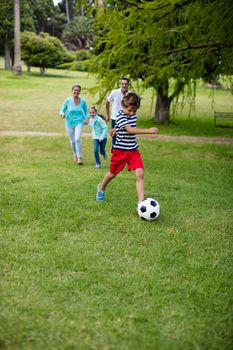 Happy family playing football in park on a sunny day