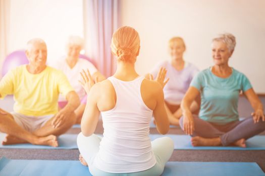 Instructor performing yoga with seniors during sports class