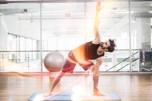 Handsome man doing yoga on mat in fitness studio