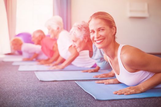 Portrait of instructor performing yoga with seniors during sports class