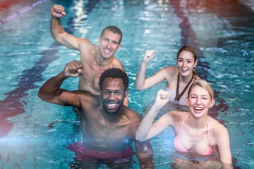 Fit people cycling in pool with arms raised