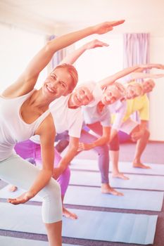 Portrait of instructor performing yoga with seniors during sports class