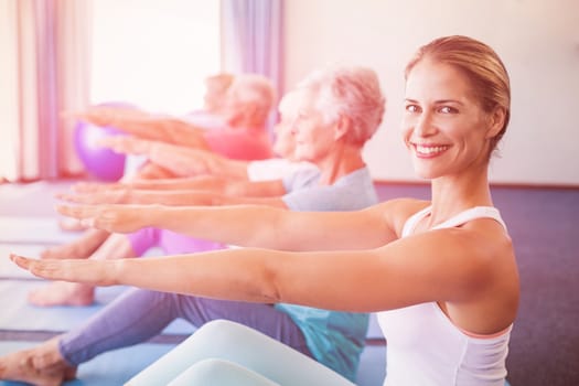 Portrait of Instructor performing yoga with seniors during sports class