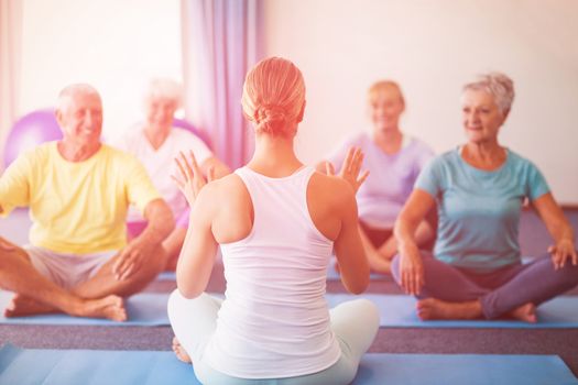 Instructor performing yoga with seniors during sports class