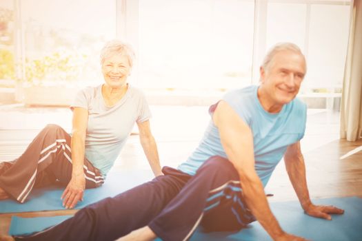 Happy senior couple doing yoga on exercise mat at home