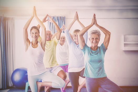 Instructor performing yoga with seniors during sports class