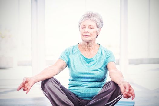 Senior woman performing yoga while sitting at home