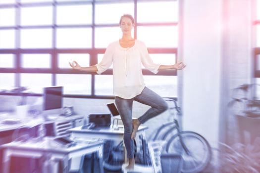 Female business executive performing yoga in office