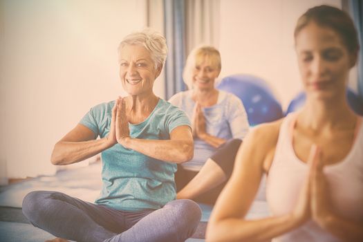 Instructor performing yoga with seniors during sports class