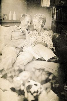 Grey background against happy romantic senior couple sitting on sofa