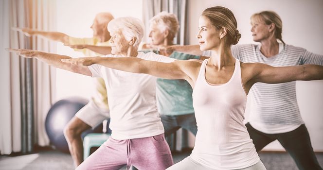 Instructor performing yoga with seniors during sports class