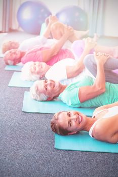 Portrait of instructor performing yoga with seniors during sports class