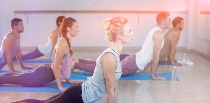 Side view of people performing yoga in gym