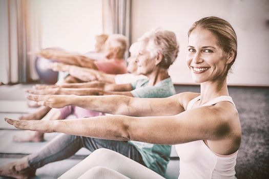 Portrait of Instructor performing yoga with seniors during sports class